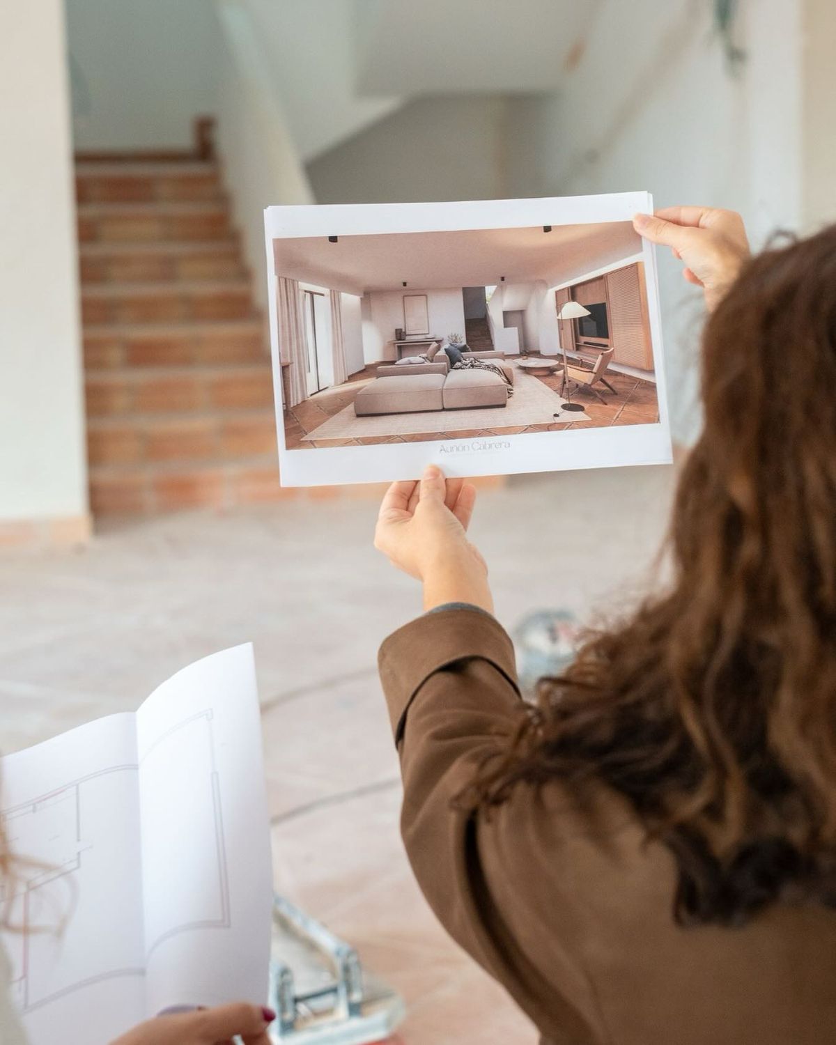 Agent holding a styled interior render inside an empty room